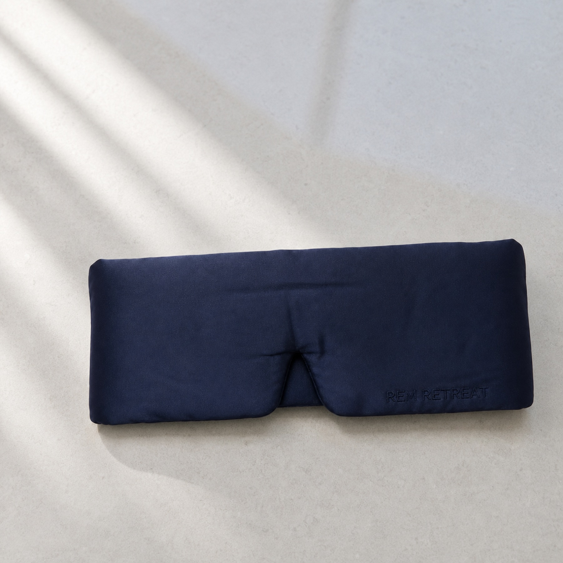 Styled product study of the midnight blue REM Retreat sleep mask
